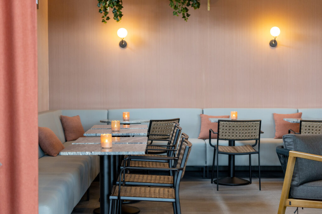 Ein elegantes Restaurant mit hellblauen Sitzbänken, Marmortischen und warmgelber Beleuchtung, die eine intime Atmosphäre schafft