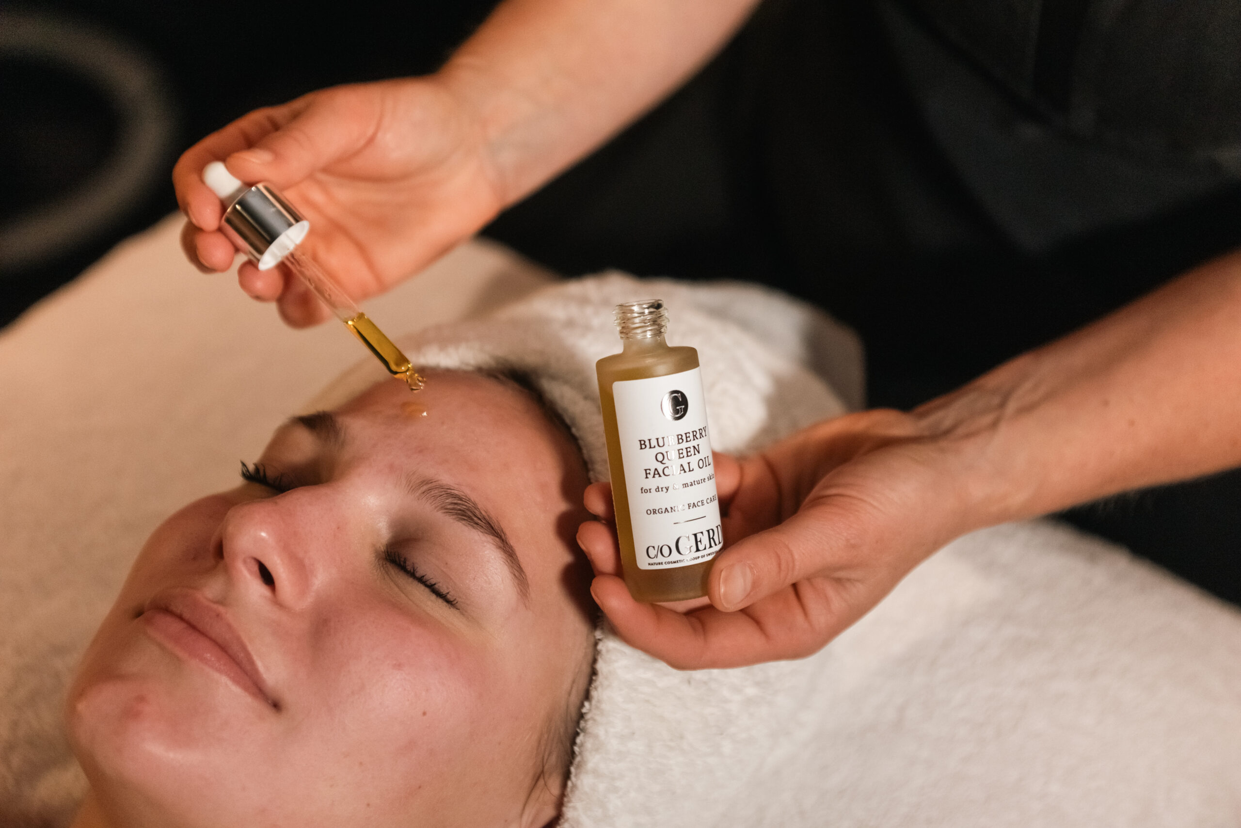Gesichtsbehandlung mit Bio-Heidelbeeröl im Starby Spa, eine Frau entspannt sich, während die Therapeutin ein Serum aufträgt