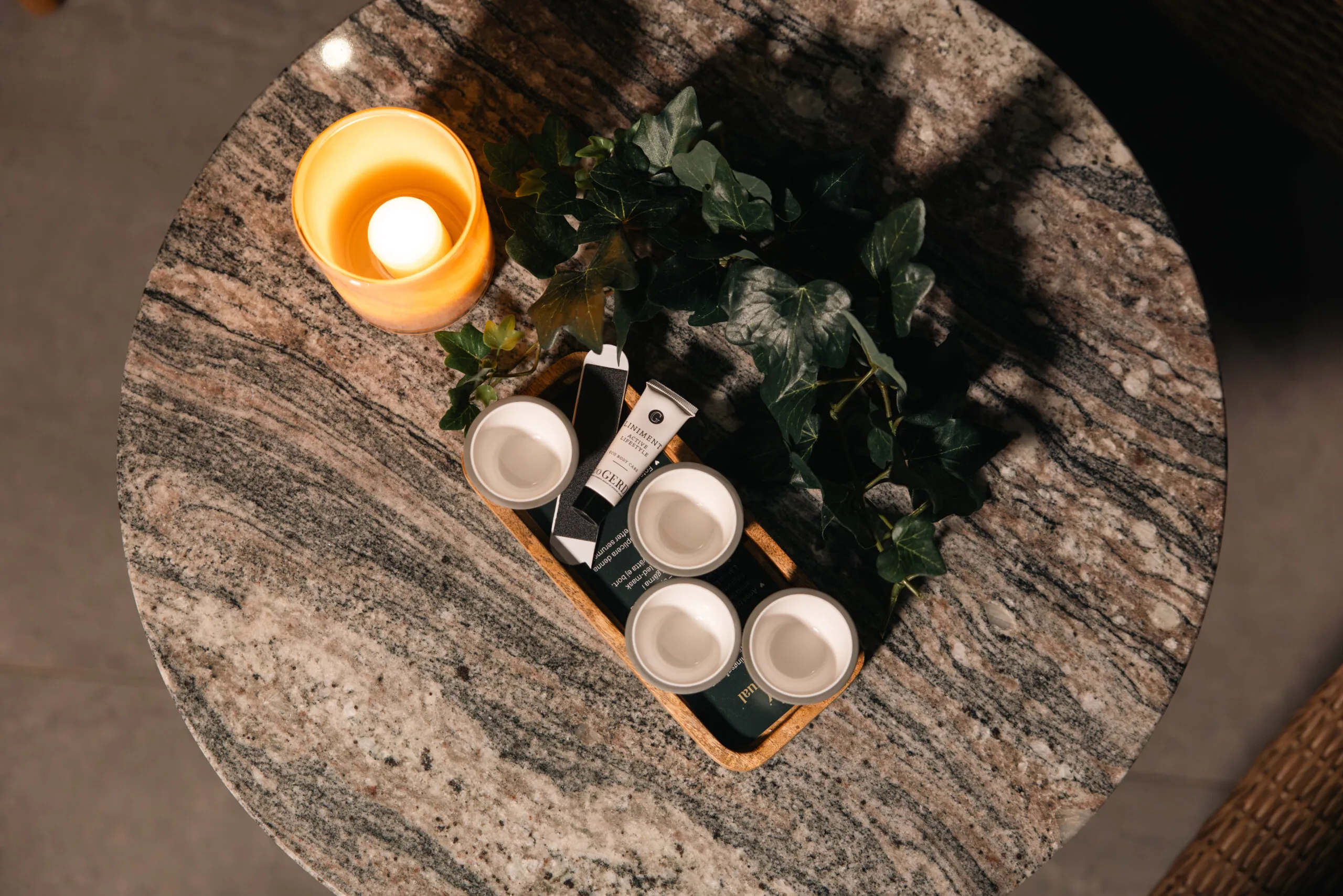 Spa-produkter arrangerade på marmorbord med tända ljus och grön växt för en avkopplande atmosfär