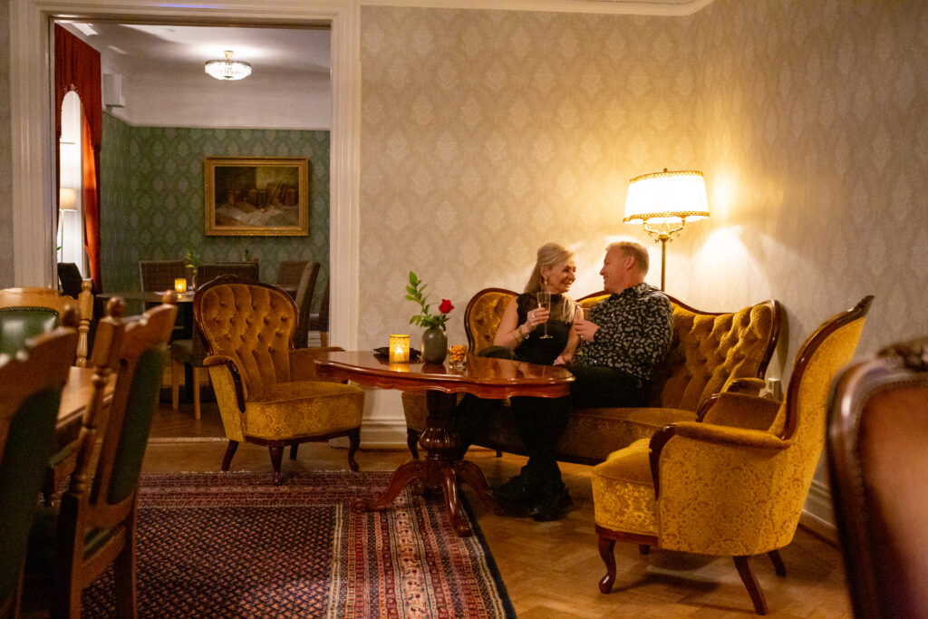 Paare genießen ein intimes Abendessen in einer eleganten Hotellobby mit klassischem Dekor und warmer Beleuchtung