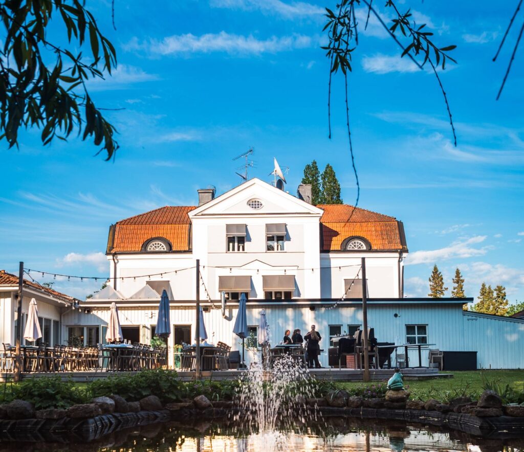Starby Spa & Hotells huvudbyggnad med orangerött tegeltak och vit fasad, omgiven av naturskön miljö vid Vättern
