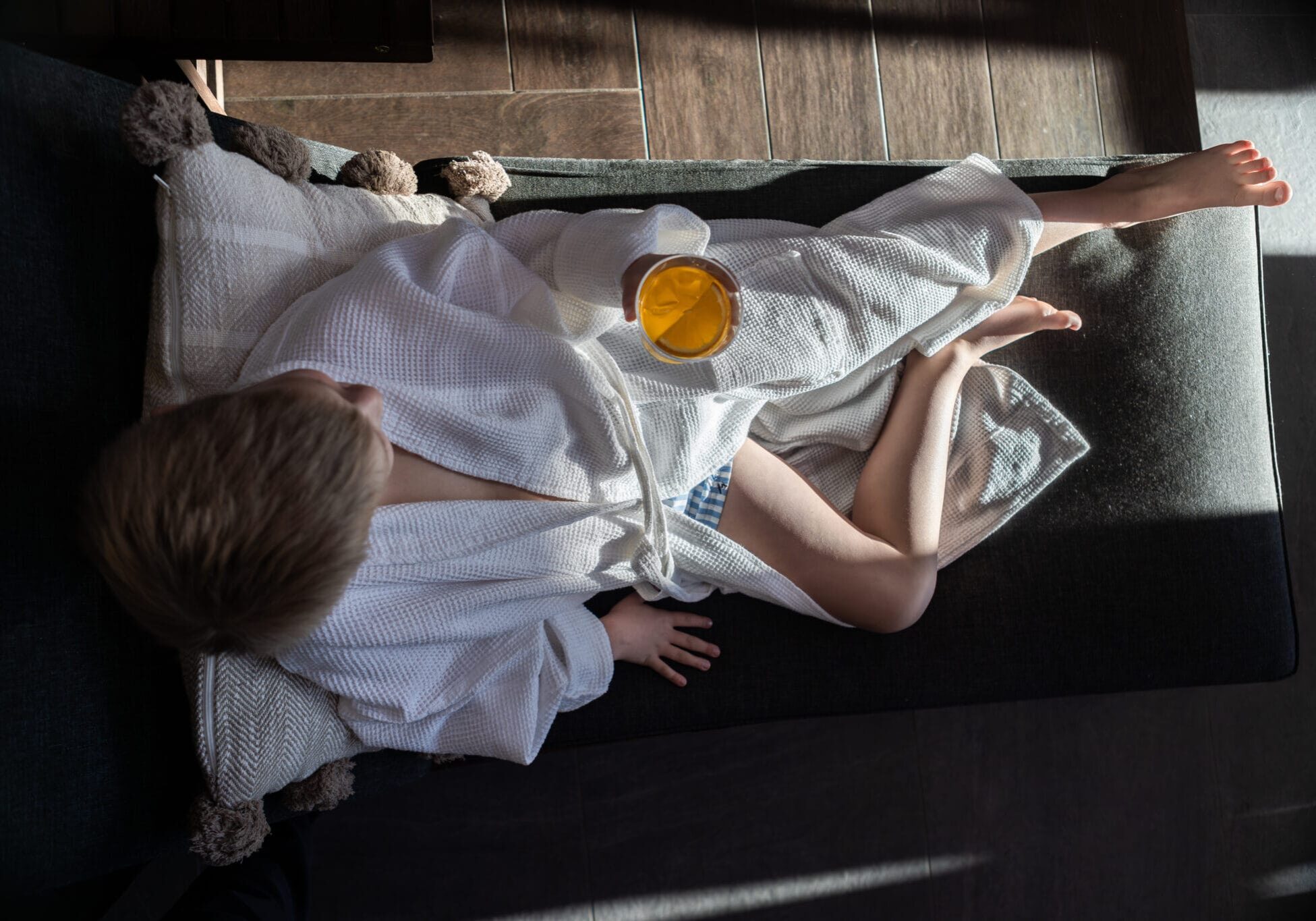 Lovrabatt – familjevänlig avkoppling på Starby Spa Barn i vit badrock vilar i soffa och håller ett glas juice – avkoppling under lovrabatt på Starby Spa & Hotell